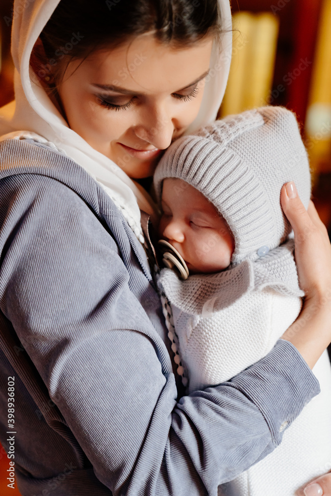 Canvas Prints beautiful mom in a headscarf with a small child in her arms in church. 