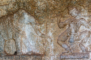 Hampi, Karnataka, India - November 4, 2013: Mural sculpture on brown stone at Royal Enclosure. Mural sculpture of elephant and man with pole on shoulders.