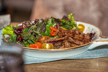 Roast beef slices with vegetables on a white dish