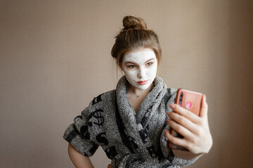 woman in clay mask takes photo on mobile phone for social media