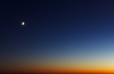 Fototapeta na wymiar The conjunction of the Moon, Jupiter and Saturn in winter. Bright evening sky after sunset.
