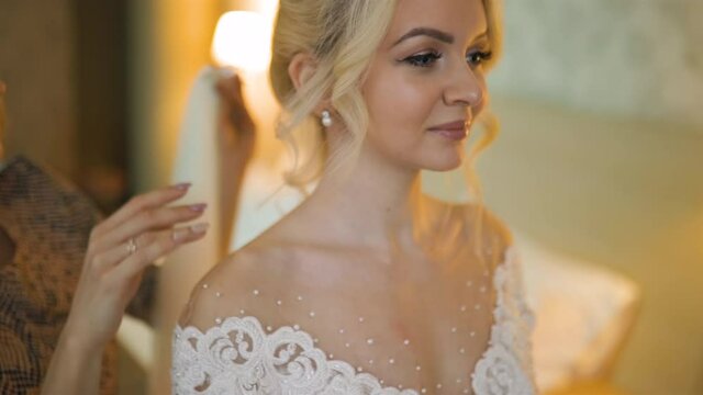 Female hands help help attach bridal veil to beutiful hairdo of young bride