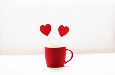 Red wooden hearts in a red cup on a white background with copy space. Valentine's Day greeting card.