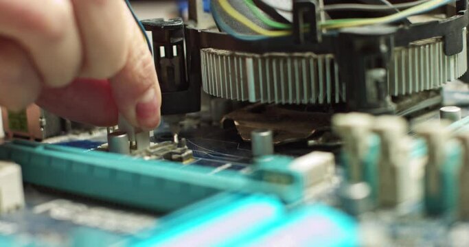 Connecting the plug to the motherboard, the wizard connects the CPU cooling. Repair and maintenance of computer boards. In Modern Electronic Manufacturing Factory Design Engineer Holds Microchip .New