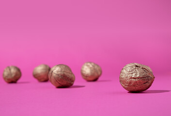 Golden walnuts in high contrast pink background