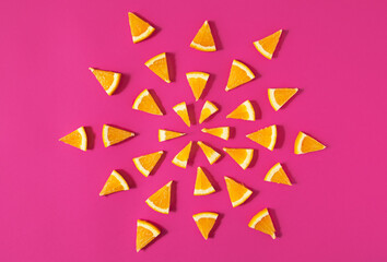 Geometric mandala from orange fruit slices on pink