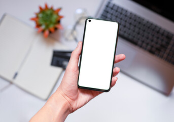 Close - up of a smartphone with a white screen in a woman's hand, Notepad in the background, credit cards, selective focus, shopping concept with a mobile phone phone with copy space, top view.