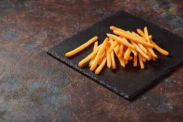 Tasty french fries on cutting board, on wooden table background