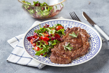Grilled steaks and vegetable salad on light background. Table setting, food concept