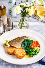 Pike perch fillet with vegetable cutlets and vegetables in the restaurant setting.