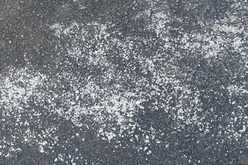 De-icing chemicals reagent on asphalt road. Pavement is sprinkled with technical salt will make the...