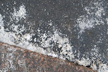 De-icing chemicals reagent on asphalt road. Pavement is sprinkled with technical salt will make the road safe, top view. 