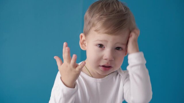 medicine, dermatology, treatment, inflammation, concepts - preschool minor toddler kid boy scratche his dandruff head, dry itchy face on blue background. Food allergies, urticaria, gluten intolerance