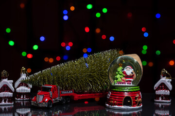 Christmas decorations, a red car with a Christmas tree on a trailer and a snow globe with Santa Claus inside.
