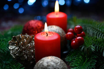 Lighted red candles surrounded by holiday decorations.