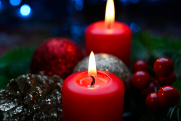 Lighted red candles surrounded by holiday decorations.