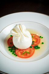 Burrata italian cheese snack with tomeatoes served on white plate