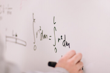 Hand writing equations on a whiteboard with a marker