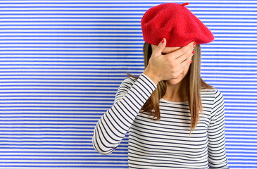 Portrait of woman that looks disappointed. She covered her face with hand. Standing in front of...