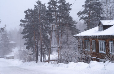 Winter landscape. Snow-covered village with old wooden houses.  road downhill is covered with snow.