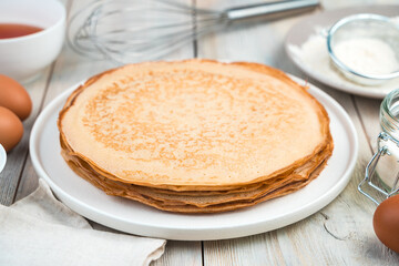 Cooking background with pancakes and ingredients on a light table. Side view. The concept of cooking, recipes, Mardi Gras.