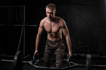 Fototapeta na wymiar a young athlete performing a deadlift with a square bar