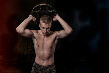Fototapeta na wymiar athlete with athletic body posing with a barbell disk on a red and blue background