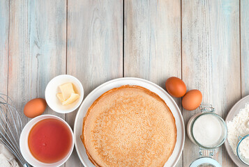 Pancakes and ingredients for cooking on a light wooden background. Top view, with space to copy. Concept of culinary backgrounds, Maslenitsa.