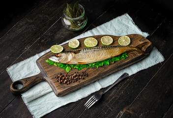 Appetizing cold smoked mackerel with ingredients on a cutting board. On dark wooden background