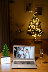 Virtual celebrating Christmas day on the distance. Laptop screen with a webcam shots of family with a baby boy, video call to relatives in holiday due coronavirus pandemic