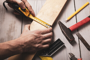 Carpenter measures the workpiece with a tape measure, tools, top view