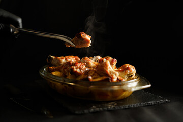 Hand holds baked chicken with potatoes