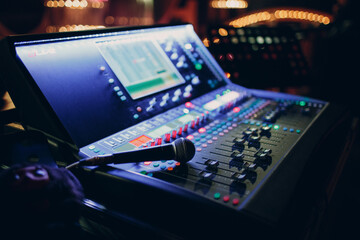 Mixing console and microphone, hand equalizing audio sound channels in night club