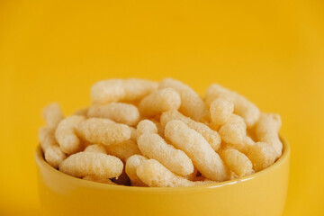 Corn sticks in a yellow bowl on a yellow background. Copy, empty space for text