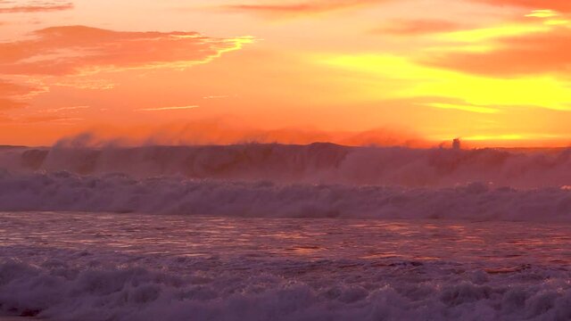 Dramatic sunset over the ocean. Huge waves and bright sky on background