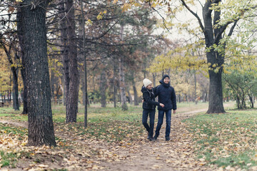 Fototapeta premium teen girl and boy walking through the park and enjoys autumn, beautiful nature with yellow leaves