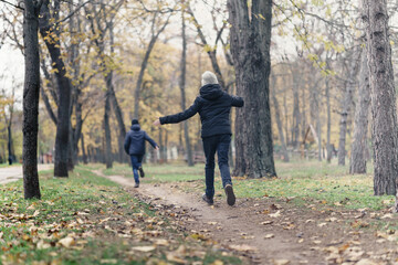 Obraz premium teen girl and boy running through the park and enjoys autumn, beautiful nature with yellow leaves