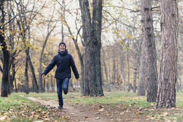 Fototapeta premium a boy running through the park and enjoys autumn, beautiful nature with yellow leaves