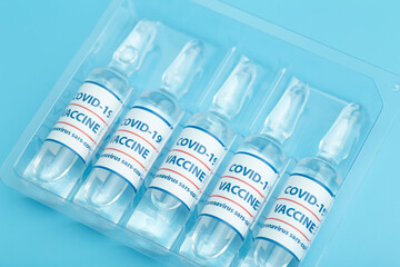 Vaccine against COVID-19. Glass medical vials with liquid. Ampoules with coronavirus vaccine on a medical glass table