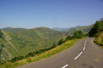 Mountain road surrounded by green meadows through the French Pyrenees