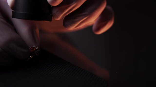 Man in protective gloves inspects golden ring and counts money. Closeup of pawnshop owner examining jewel with magnifying glass. Theme of business professional occupation. Buying of precious metals