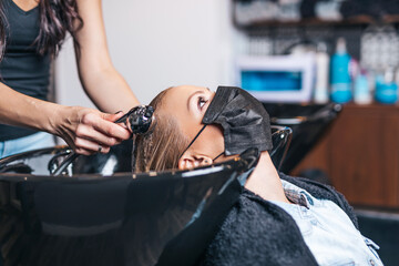 ProfeBeautiful middle-aged woman with protective face mask in hair salon.