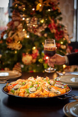 Spanish dinner table with assortment of dishes. paella, octopus, whole fish, sangría and wine. Dressed for christmas