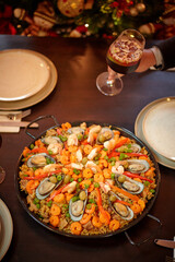 Spanish dinner table with assortment of dishes. paella, octopus, whole fish, sangría and wine. Dressed for christmas