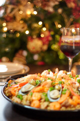 People sharing Spanish dinner table with assortment of dishes. paella, octopus, whole fish, sangría and wine. Dressed for christmas