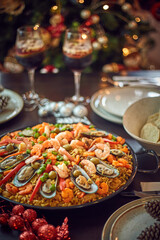 Spanish dinner table with assortment of dishes. paella, octopus, whole fish, sangría and wine. Dressed for christmas