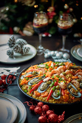 Spanish dinner table with assortment of dishes. paella, octopus, whole fish, sangría and wine. Dressed for christmas