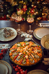 Spanish dinner table with assortment of dishes. paella, octopus, whole fish, sangría and wine. Dressed for christmas