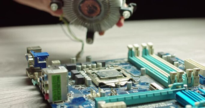The wizard removes CPU cooling for diagnostics. Repair and maintenance of computer boards and the latest processors. Replacement of chip thermal paste. In Modern Electronic Manufacturing Factory
