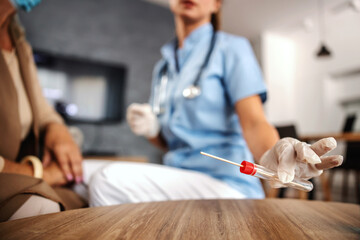 Closeup of nurse putting cotton swab form an old woman and putting it on a table while sitting at home.